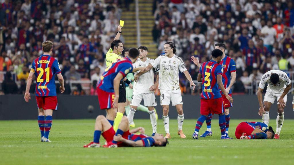 L'àrbitre José Luis Munuera Montero ensenya una targeta groga a Fede Valverde després d'una disputa amb Raphinha