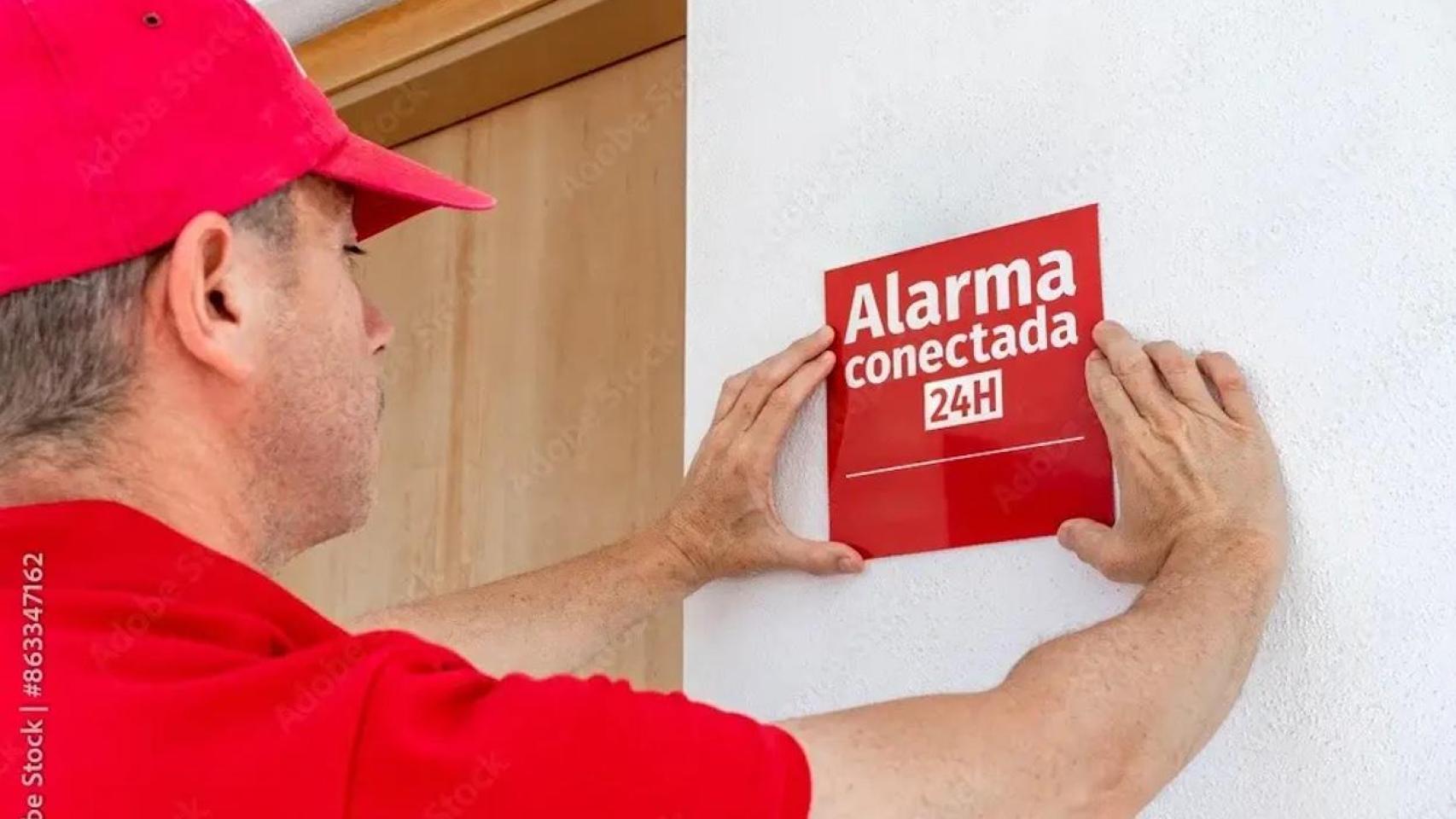 Instalador coloca un cartel de aviso de alarma conectada