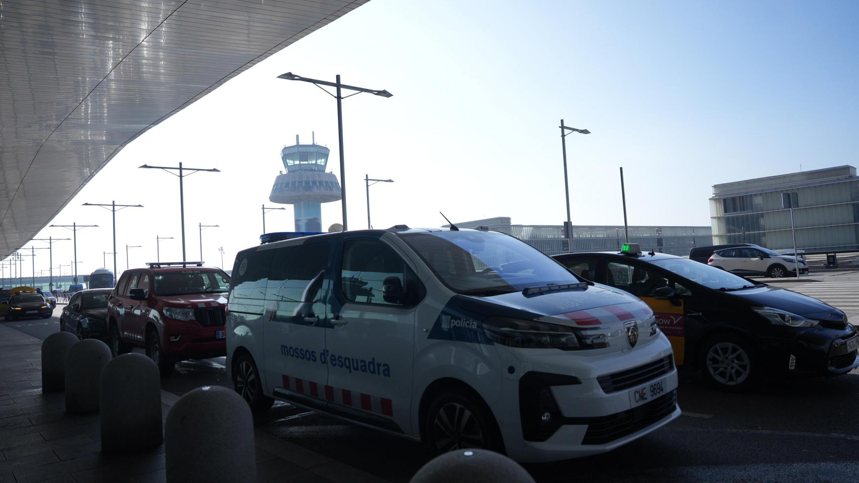 Un vehículo de los Mossos d'Esquadra y una torre de control de fondo en el Aeropuerto Josep Tarradellas Barcelona - El Prat, después de registrarse una amenaza de bomba
