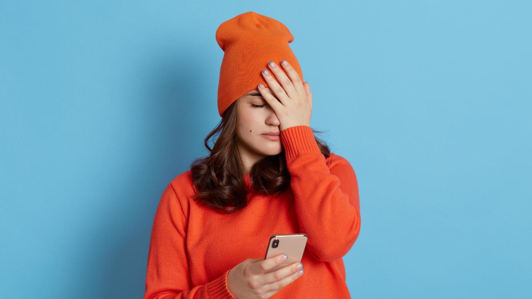 Persona tocándose la frente y con el móvil