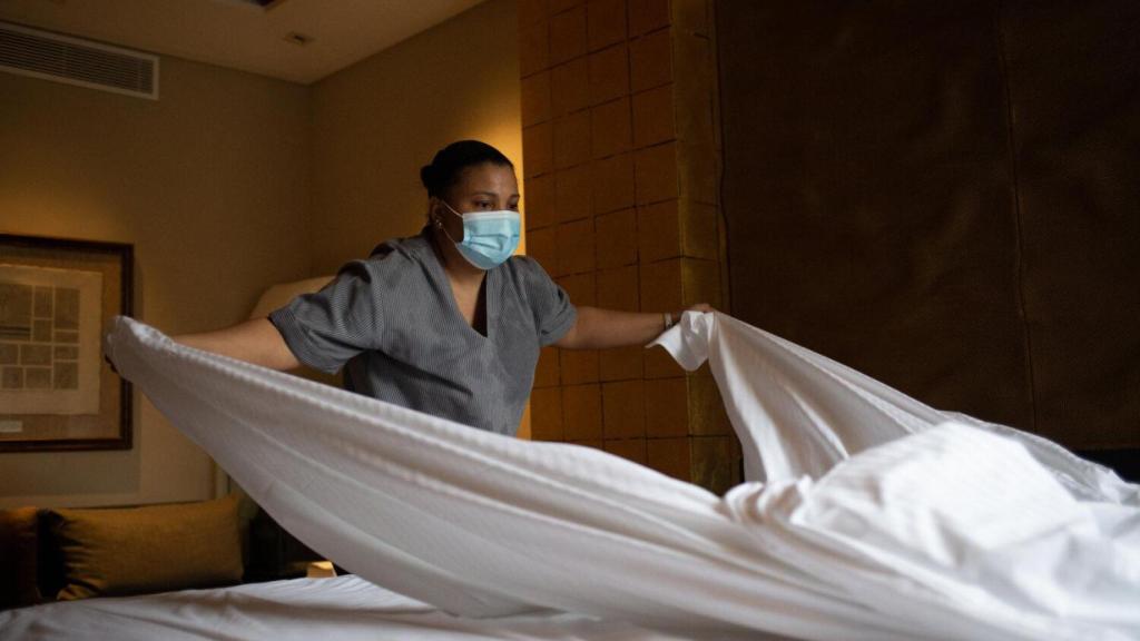 Una cambrera de pisos canvia els llençols d'un llit d'una habitació d'hotel