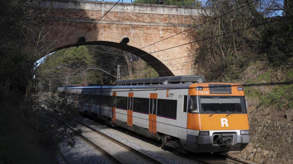 Un convoy de Rodalies de la R11 circula por debajo de un puente en Caldes de Malavella (Girona)
