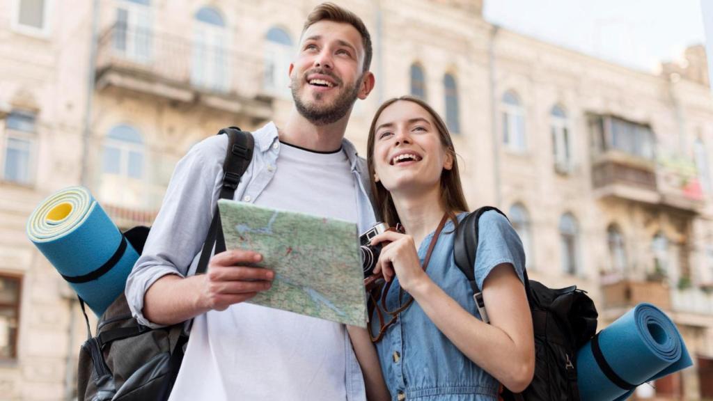 Ángulo bajo de pareja de turistas sonriente con mapa