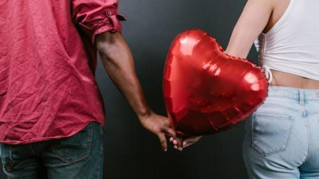 Una pareja se da la mano con un corazón inflable