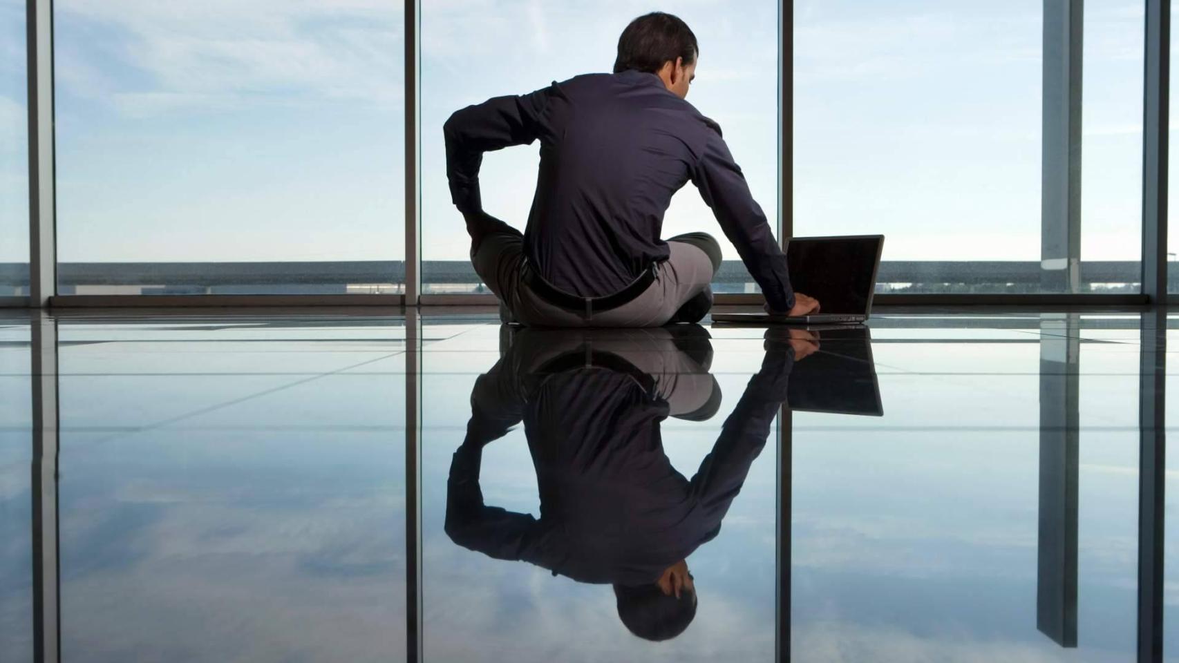 Hombre con un ordenador portátil frente a un ventanal