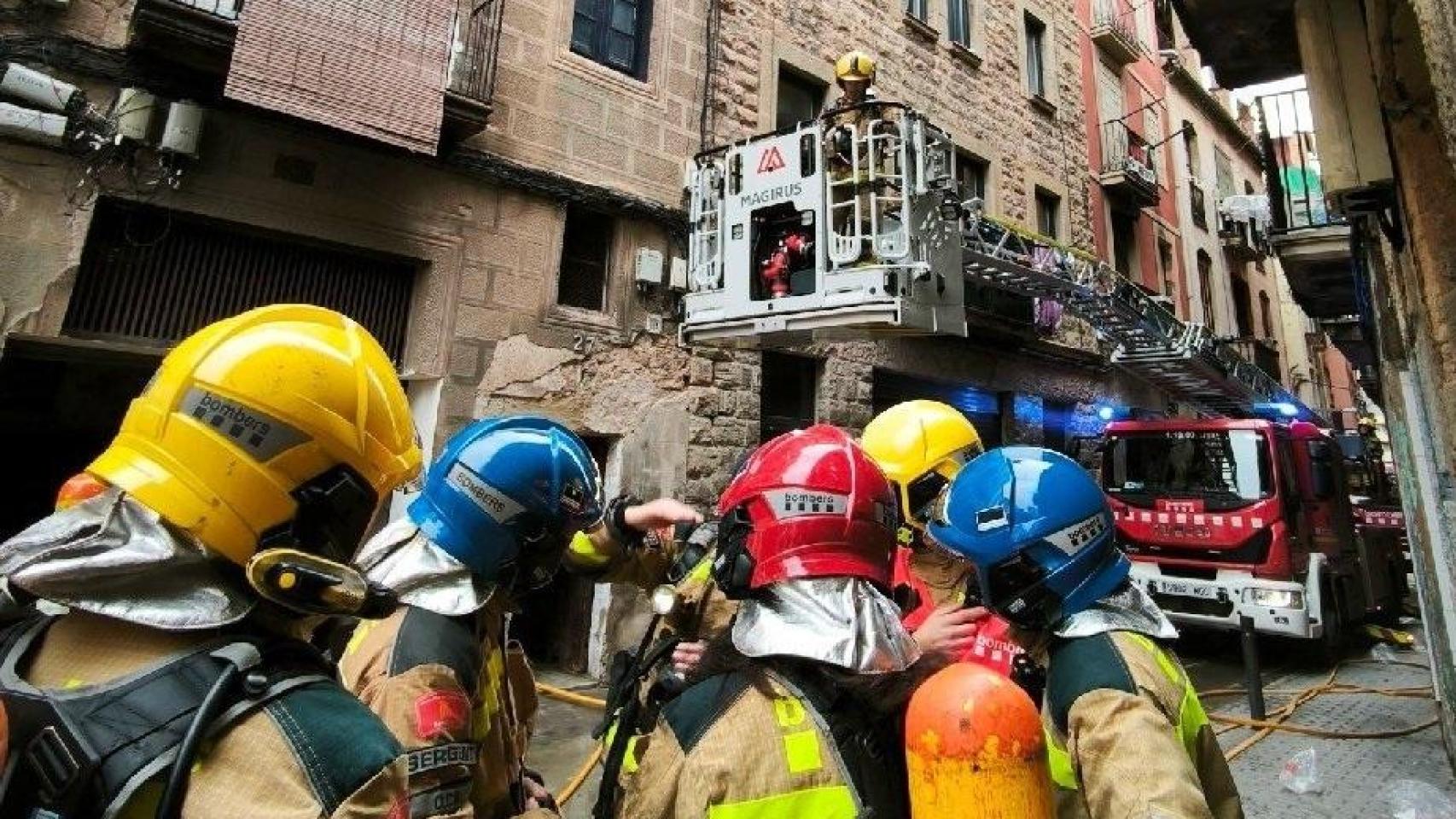Los bomberos ante el edificio incendiado en Manresa
