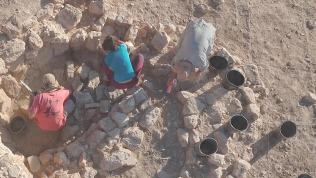 Fotomontaje con una fotografía de una excavación arqueológica y el loco del sindicato CNT