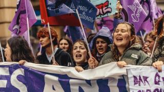 Mujeres y estudiantes sostienen pancartas y banderas moradas mientras marchan durante una manifestación con motivo del Día Internacional de la Mujer (8M) en Barcelona