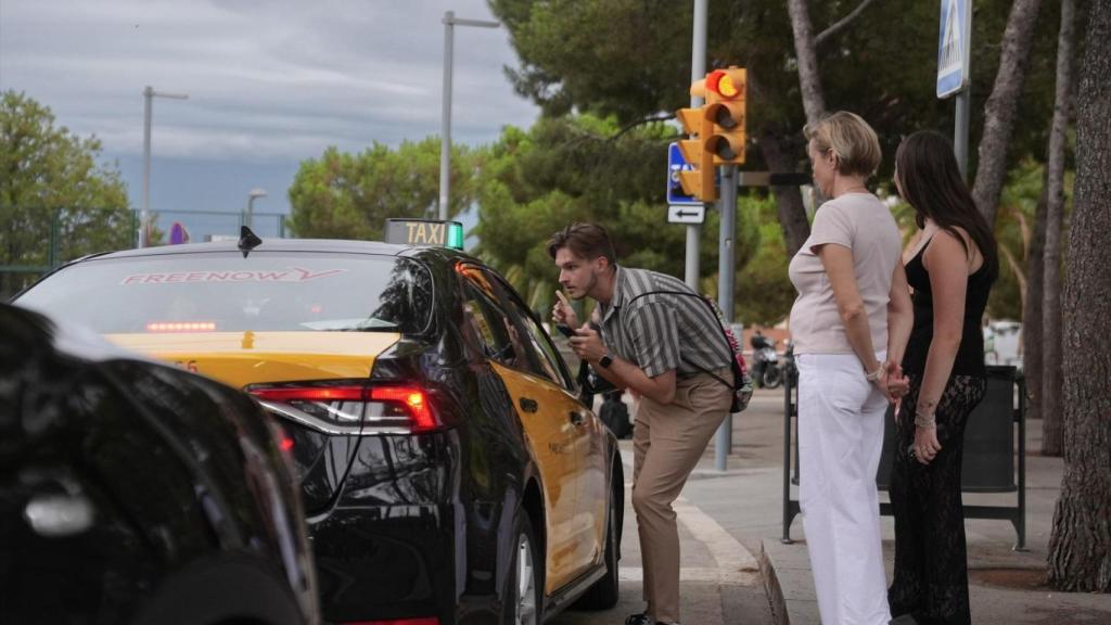 Diverses persones conversen amb un taxista en una parada de taxis del Park Güell, a 24 de juliol de 2025, a Barcelona, Catalunya (Espanya).