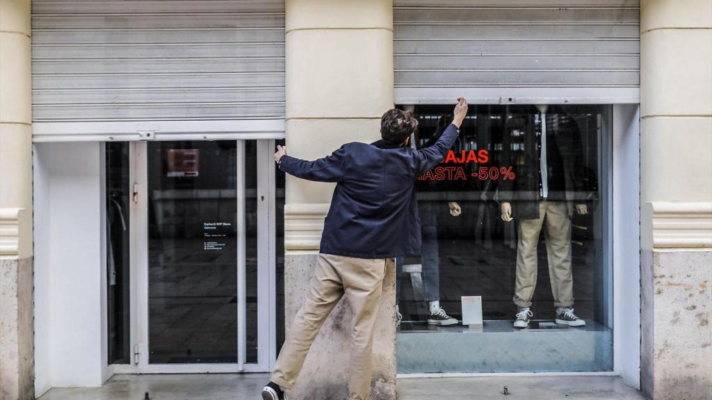 El treballador d'un comerç tanca el seu establiment el primer dia del tancament total de l'hostaleria i de botigues per el coronavirus