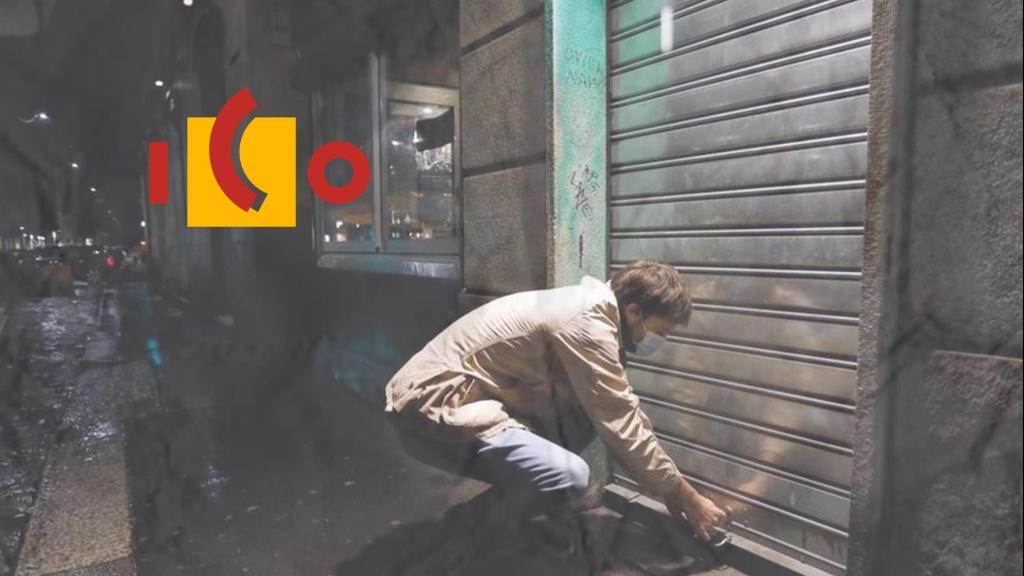 Un treballador baixant la persiana del seu comerç durant la pandèmia del coronavirus