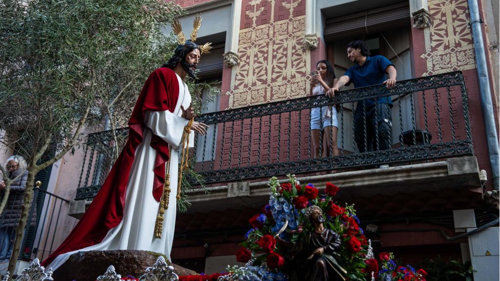 Una nena fotografia el pas del Jesús Cautiu pel seu carrer durant el Diumenge de Rams