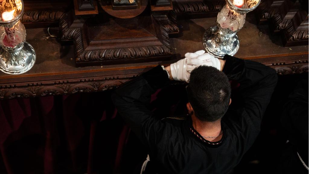 Un jove resa a la imatge del Jesús Cautiu abans de treure'l en processó el Diumenge de Rams