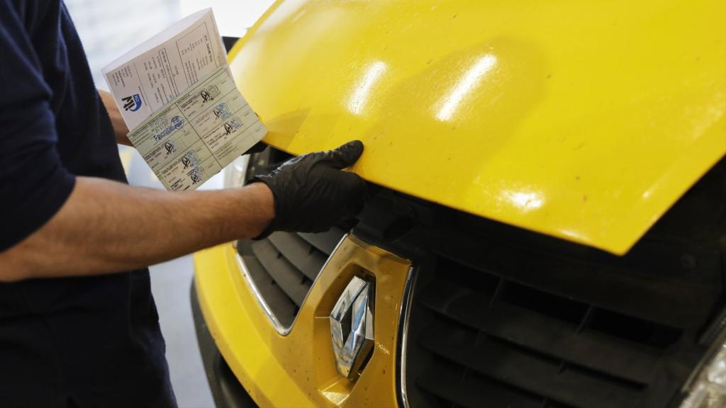 Un treballador revisa el motor d'un vehicle a la ITV