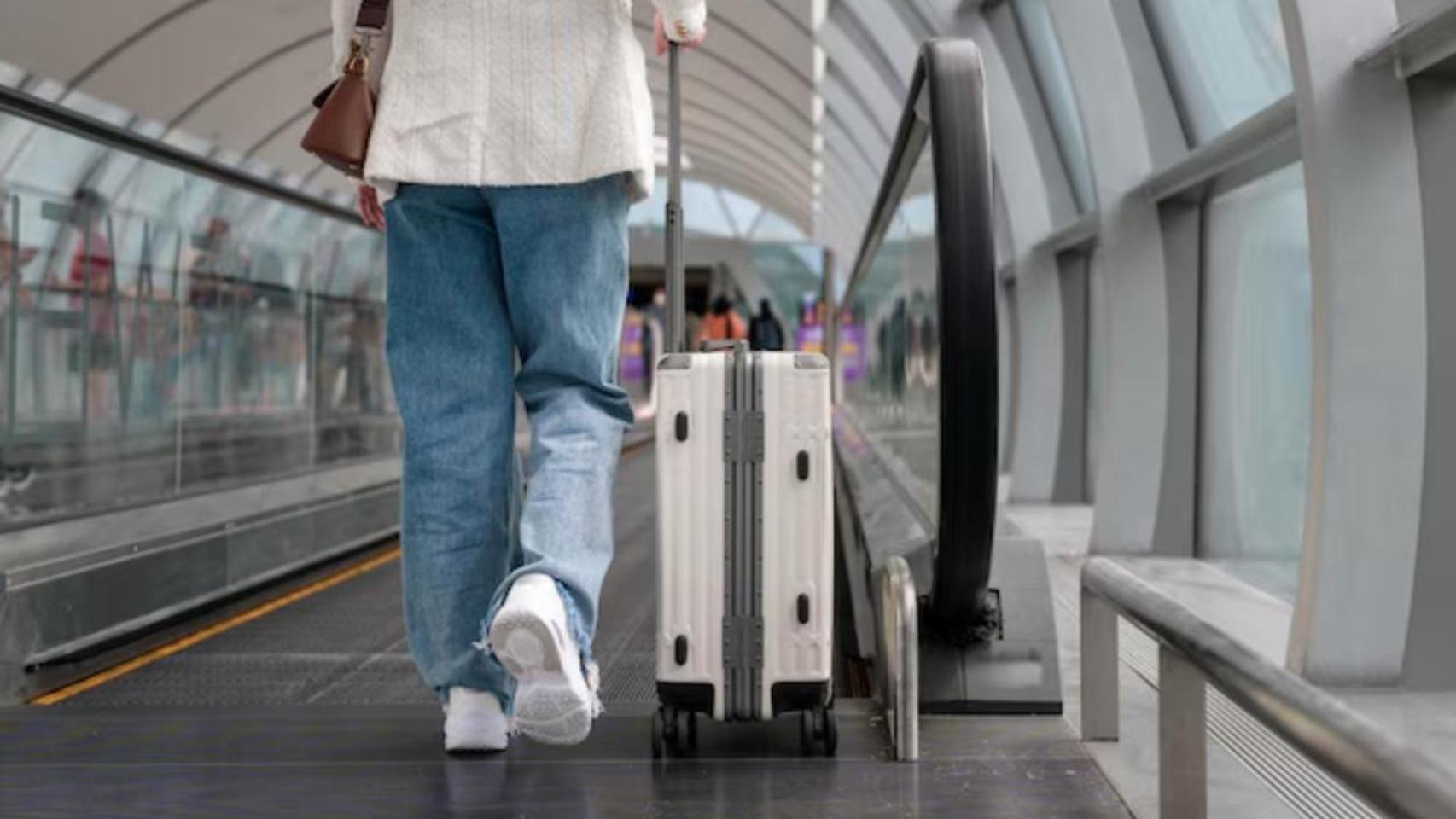 Mujer a pie lleva su maleta por un terminal de aeropuerto
