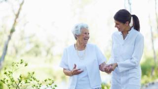 Una trabajadora pasea junto a una mujer de avanzada edad