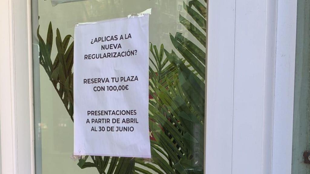 Un cartel de una gestoría de Barcelona que anuncia: ¿Aplicas a la nueva regularización? Reserva tu plaza con 100,00€.