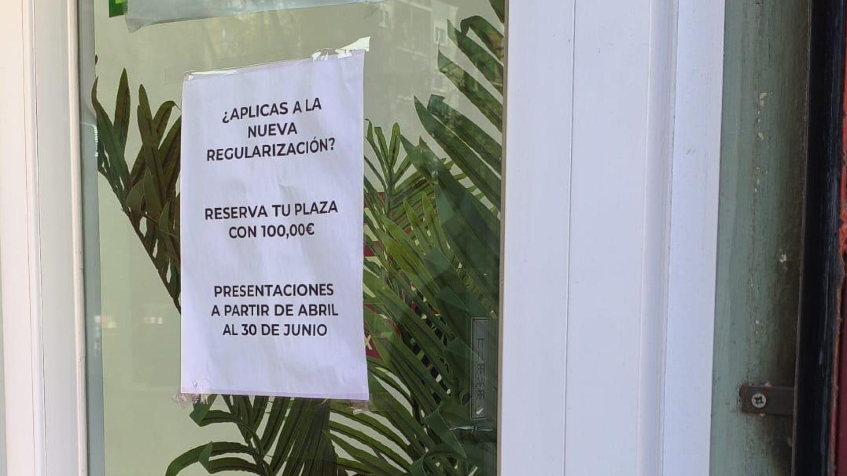 Un cartel de una gestoría de Barcelona que anuncia: ¿Aplicas a la nueva regularización? Reserva tu plaza con 100,00€.