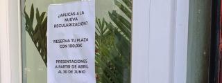 Un cartel de una gestoría de Barcelona que anuncia: ¿Aplicas a la nueva regularización? Reserva tu plaza con 100,00€.