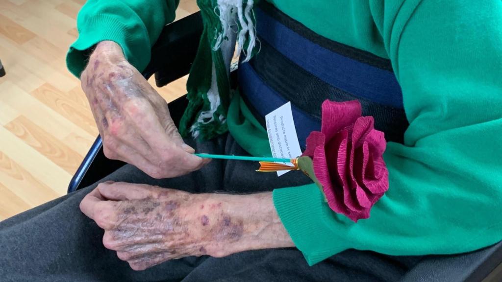 Una persona mayor con una de las rosas entregadas por los voluntarios de CaixaBank