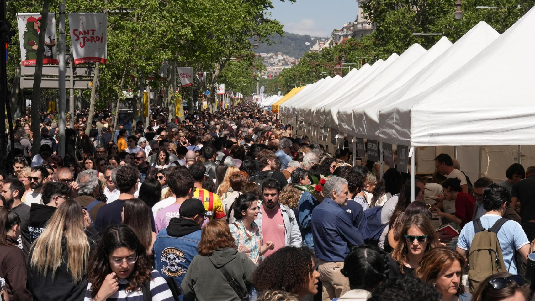 Multitud de personas esperando turno este mediodía para adquirir libros en las paradas de la plaza de Catalunya de Barcelona