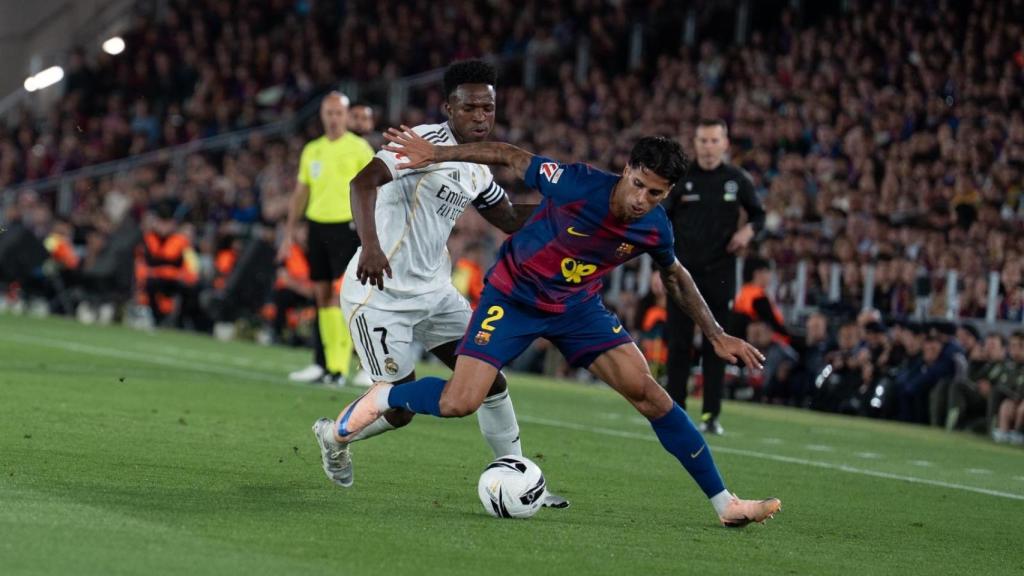Joao Cancelo protege el balón frente a Vinicius Júnior