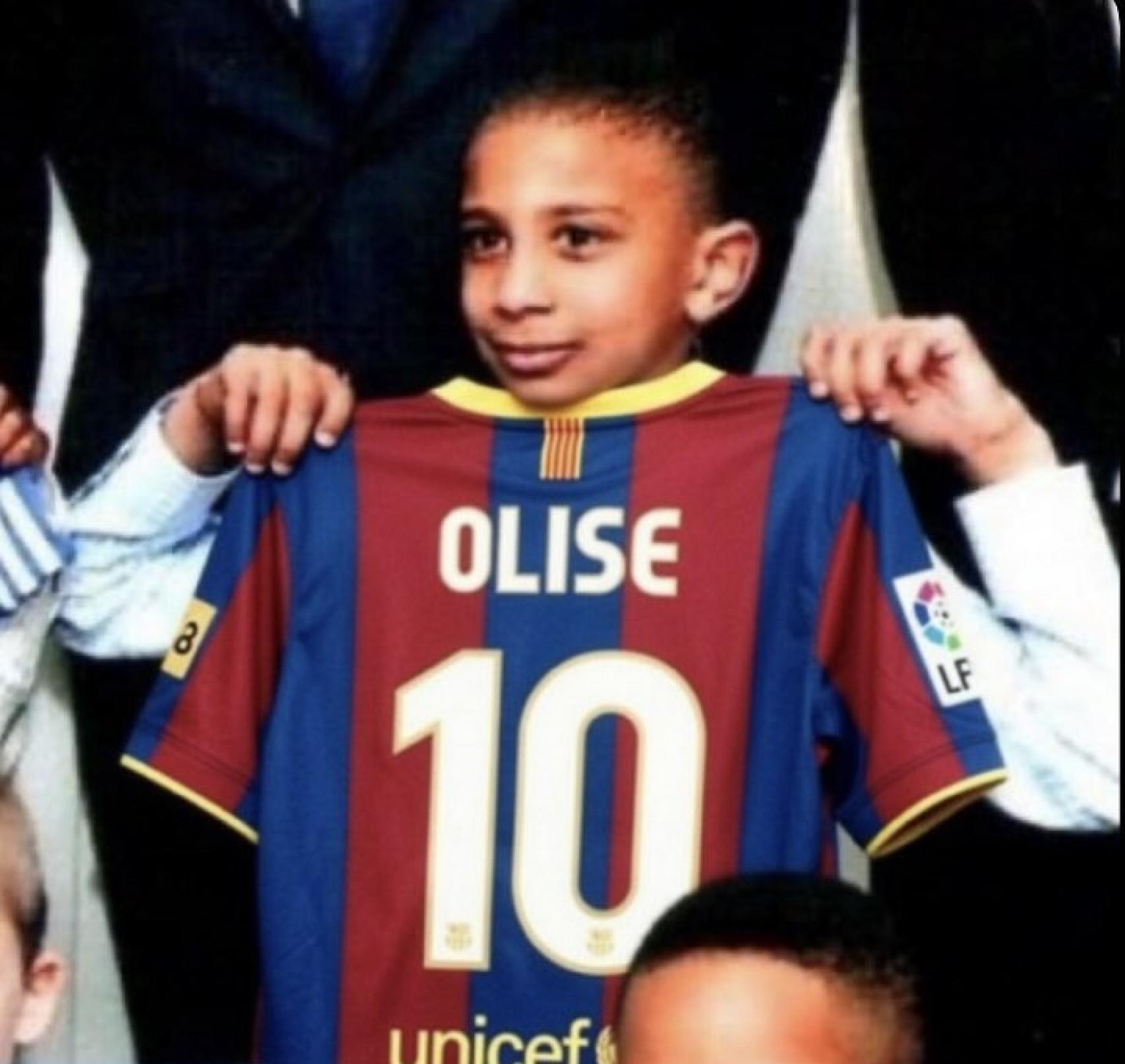 Michael Olise, de petit, sostenint una samarreta del Barça