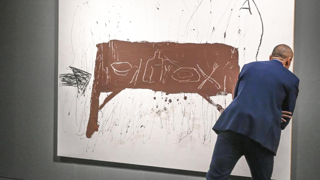 Un visitant s'acosta a una de les obres de Tàpies exposada a València.