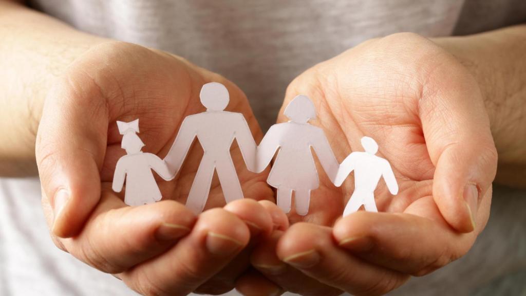 Manos sosteniendo una figura de familia, símbolo de gestión compartida y cuentas bancarias familiares.