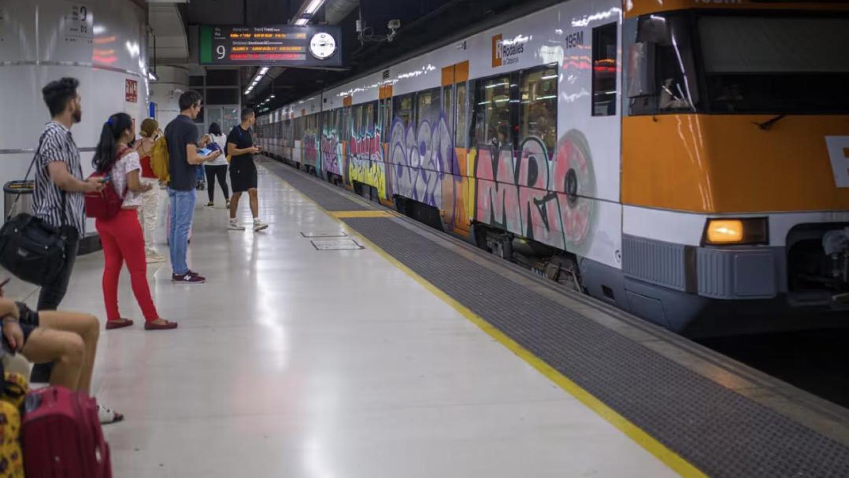 iajeros esperan la llegada de un tren en uno de los andenes de la estación de Sants