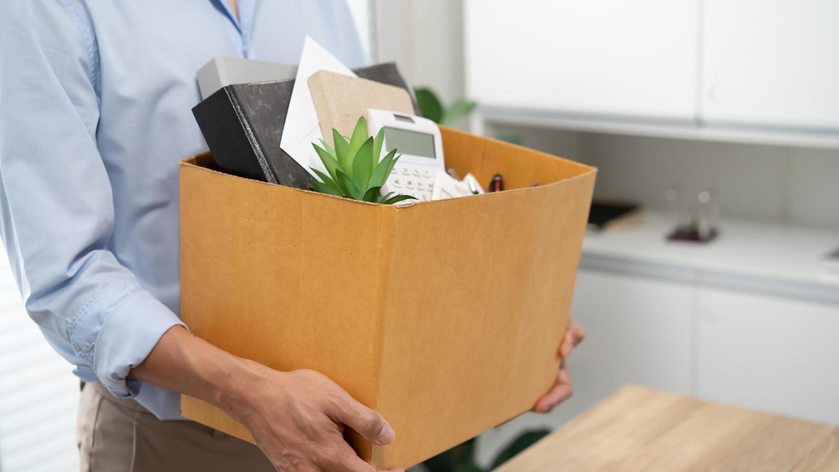 Trabajador con caja de oficina tras un despido laboral relacionado con el fin de su jornada de trabajo.