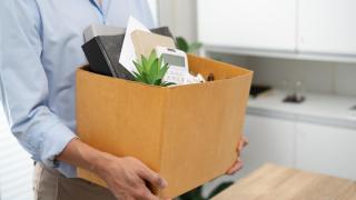 Trabajador con caja de oficina tras un despido laboral relacionado con el fin de su jornada de trabajo.