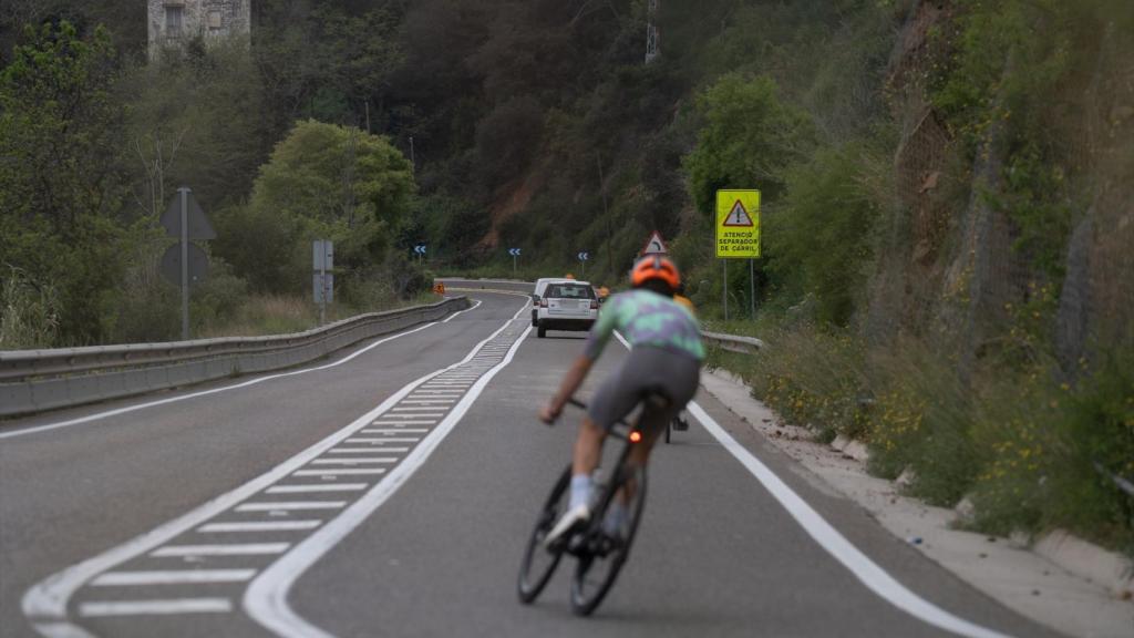 Una bicicleta y varios coches circulan por la carretera de l’Arrabassada