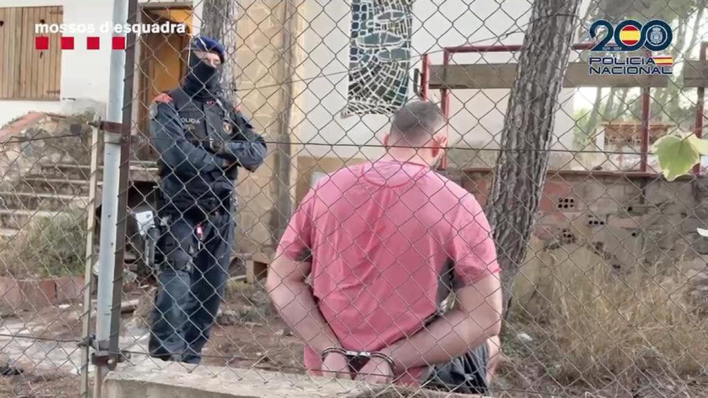 Uno de los detenidos en Cabra del Camp (Tarragona), custodiado por un agente de los Mossos d'Esquadra