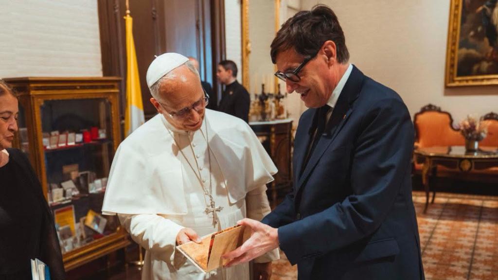 El presidente de la Generalitat, Salvador Illa, entrega un obsequio al Papa León XIV en el Palau Episcopal de Barcelona, acompañados por la mujer del dirigente catalán, Marta Estruch, a 9 de junio de 2026