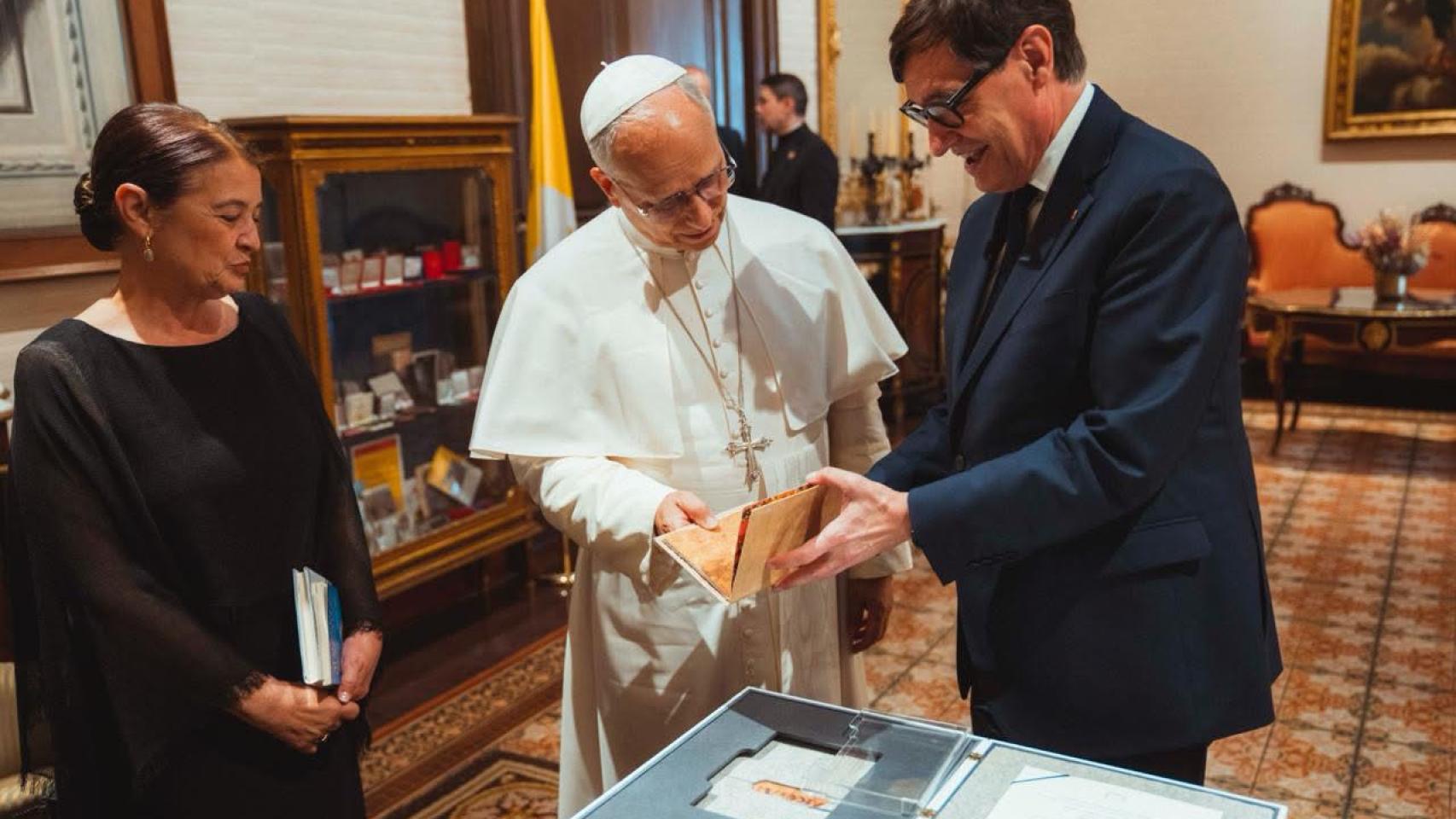El presidente de la Generalitat, Salvador Illa, entrega un obsequio al Papa León XIV en el Palau Episcopal de Barcelona, acompañados por la mujer del dirigente catalán, Marta Estruch, a 9 de junio de 2026