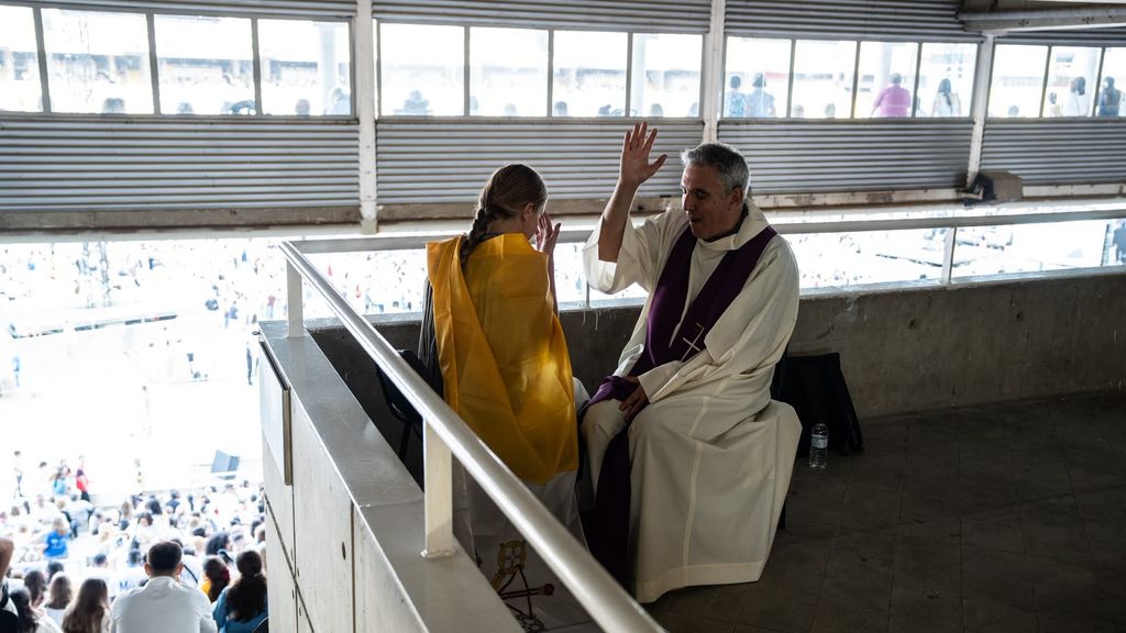 Un sacerdot confessa una jove, durant la vetlla del Papa a l'Estadi Olímpic