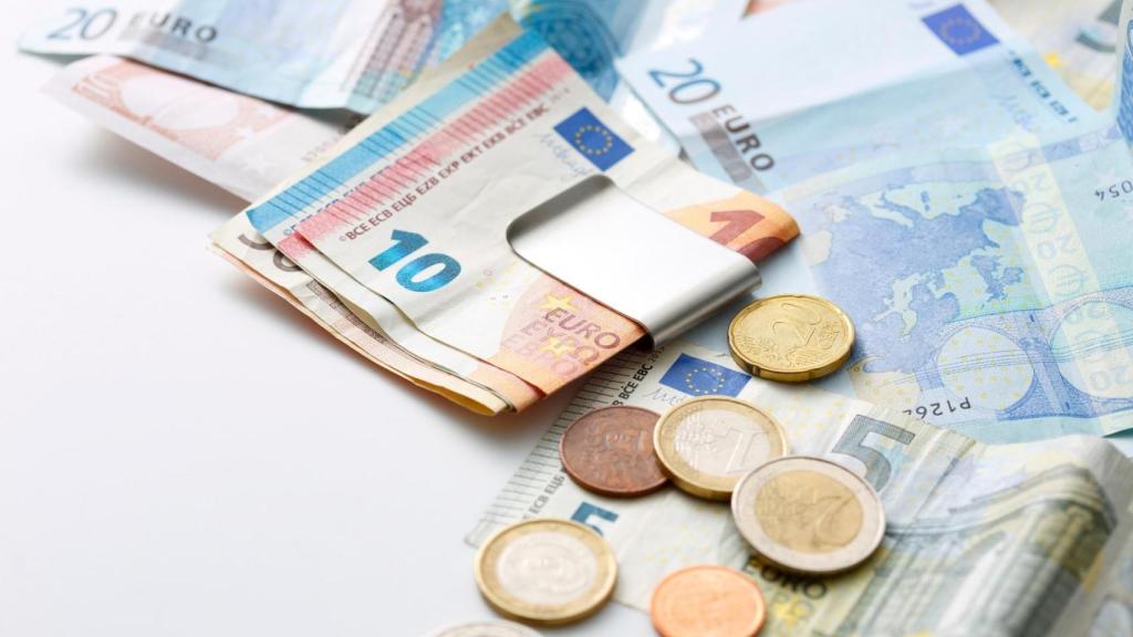 Billetes y monedas de euro sobre una mesa, imagen relacionada con el dinero en efectivo que debes guardar en casa para emergencias.