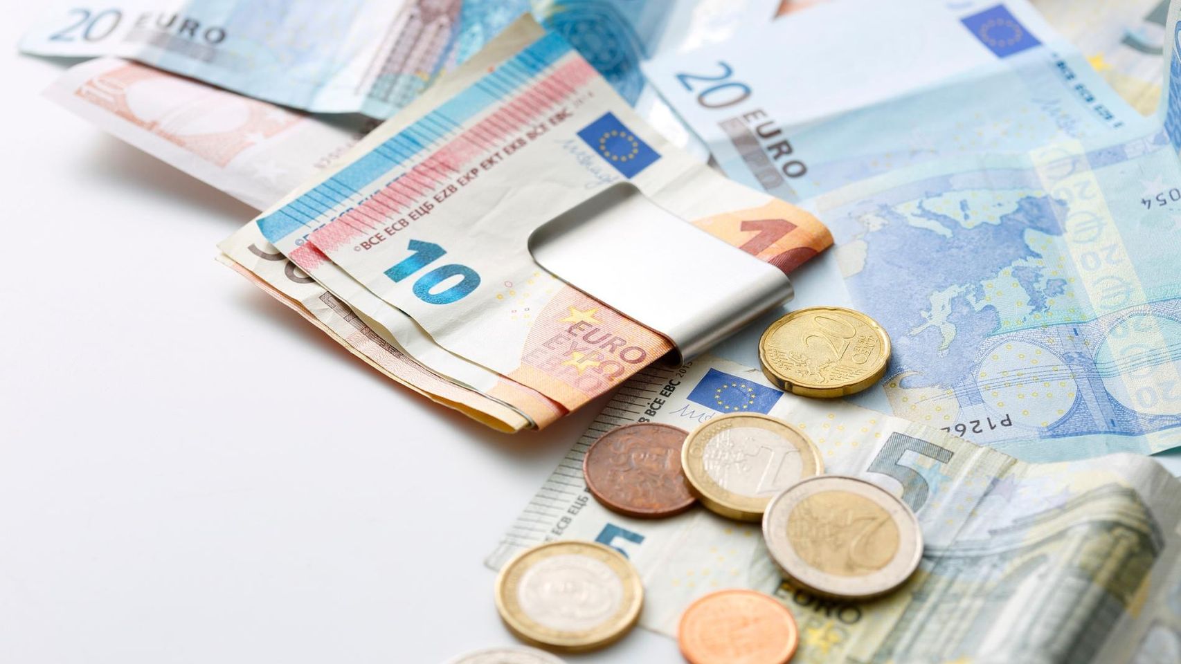 Billetes y monedas de euro sobre una mesa, imagen relacionada con el dinero en efectivo que debes guardar en casa para emergencias.