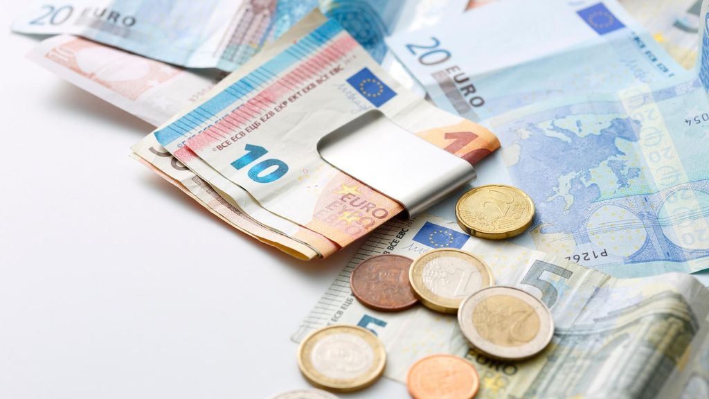 Billetes y monedas de euro sobre una mesa, imagen relacionada con el dinero en efectivo que debes guardar en casa para emergencias.