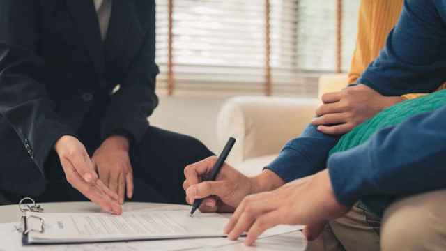 Unos jóvenes firman el contrato de alquiler.