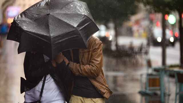 Un hombre se protege de la lluvia en la Gran Vía de Madrid.