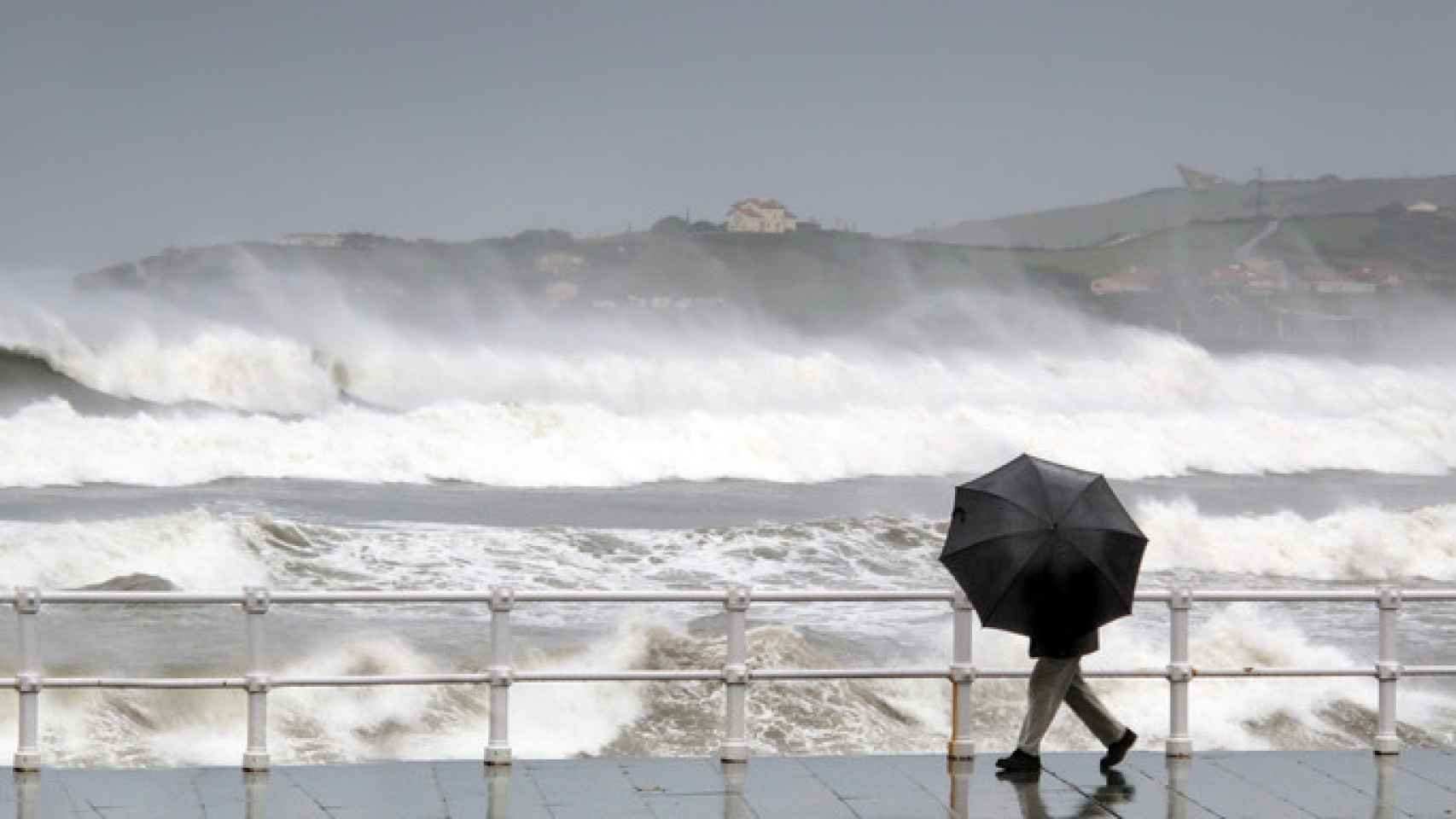 Un hombre se protege de la lluvia y el viento.