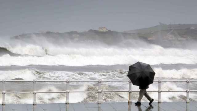 Un hombre se protege de la lluvia y el viento.