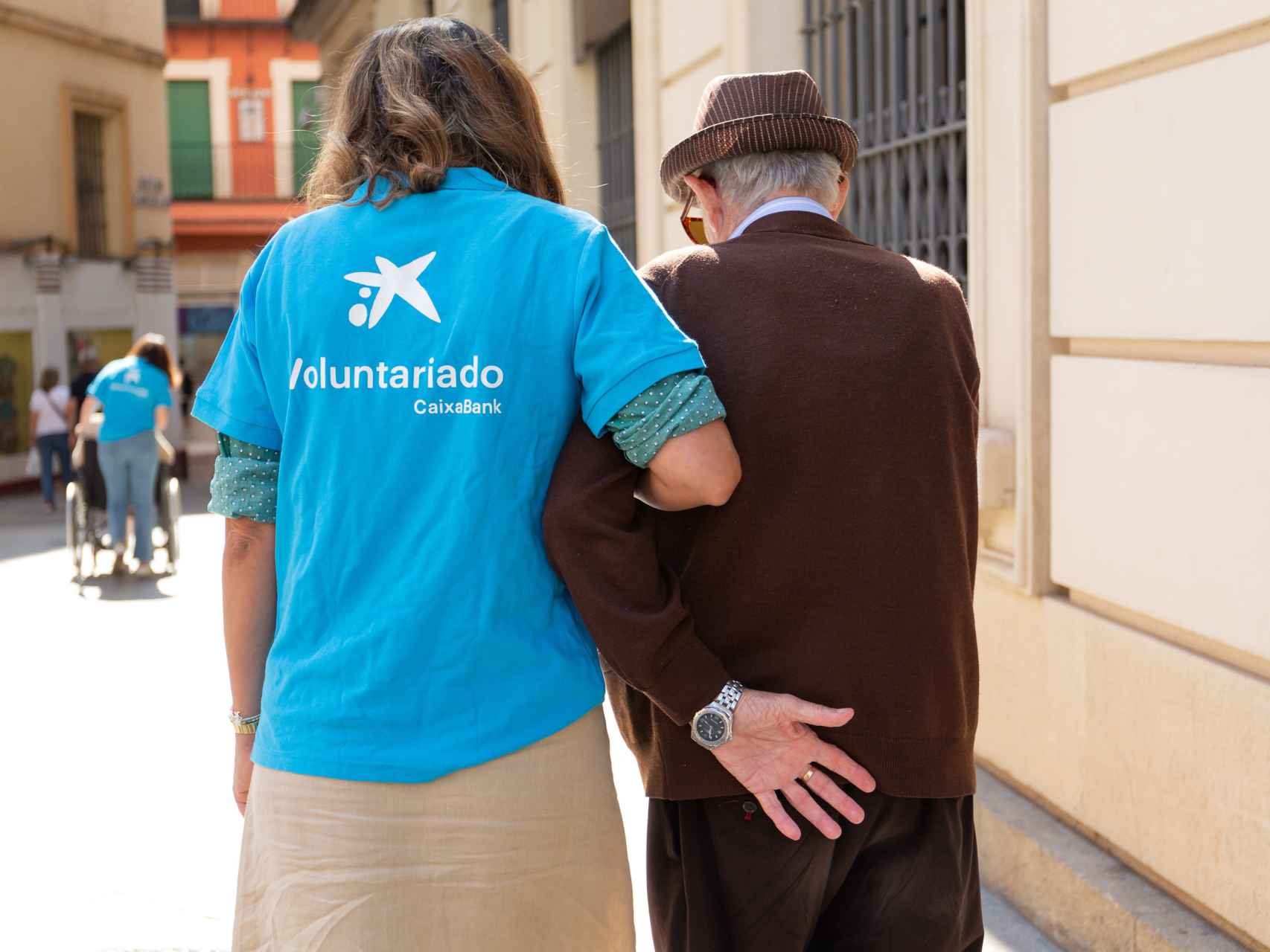 Una joven voluntaria camina junto a un hombre mayor