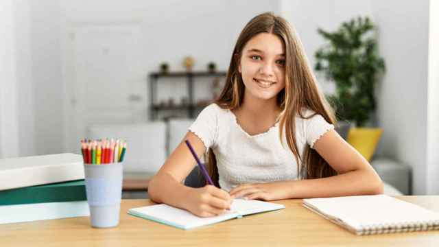 Una niña realiza unas tareas en la mesa.