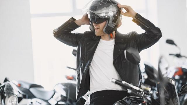 Un motorista se coloca el casco sobre la moto