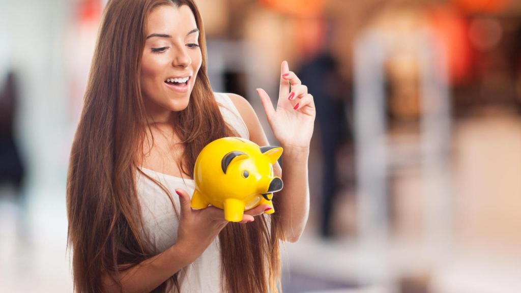 Una joven sostiene una hucha para ahorrar.