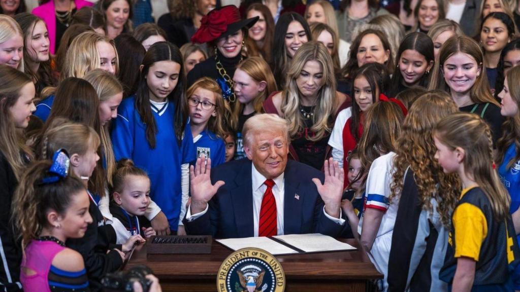 El presidente de Estados Unidos, Donald Trump, rodeado de jóvenes atletas femeninas, firma una orden ejecutiva que prohíbe a las atletas transgénero participar en deportes femeninos.