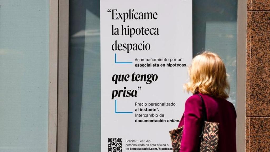 Una mujer frente a un cartel bancario sobre las hipotecas